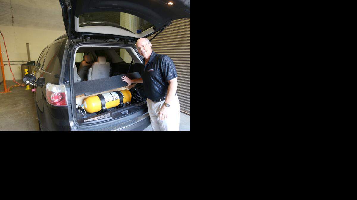 
George Bruce, CEO of Sterling CNG, shows off the compressed natural gas tank that runs his SUV. He is starting to market these systems to businesses with a fleet of vehicles. This tank holds the equivalent of four gallons of gasoline. It is being filled up using a hose on the left just below the gas tank. The vehicle can easily switch from compressed natural gas to gasoline. (August 19, 2014) 
