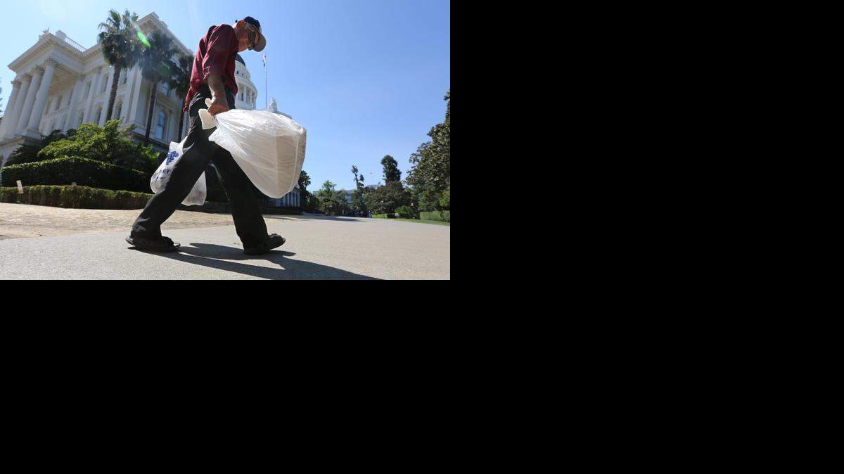
A shopper carries bags near the State Capitol in Sacramento, Calif., in August. Gov. Jerry Brown on Tuesday signed legislation that imposes the nation’s first statewide ban on single-use plastic bags.
