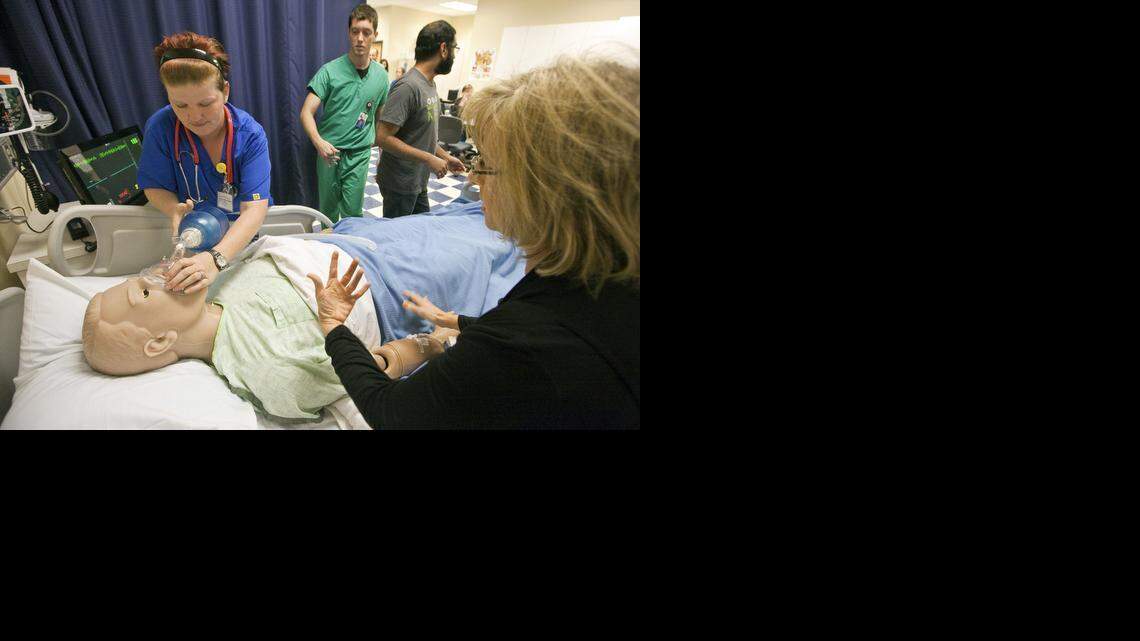 
National American University nursing student Jaime Poore, left, and Beth Bowman, NAU pre-nursing advisor, foreground, work to revive Bowman's "husband," a simulation patient who has gone into cardiac arrest. Students and faculty from area medical and nursing schools got hands-on training using medical simulation dummies at National American University. (Oct. 31, 2013)
