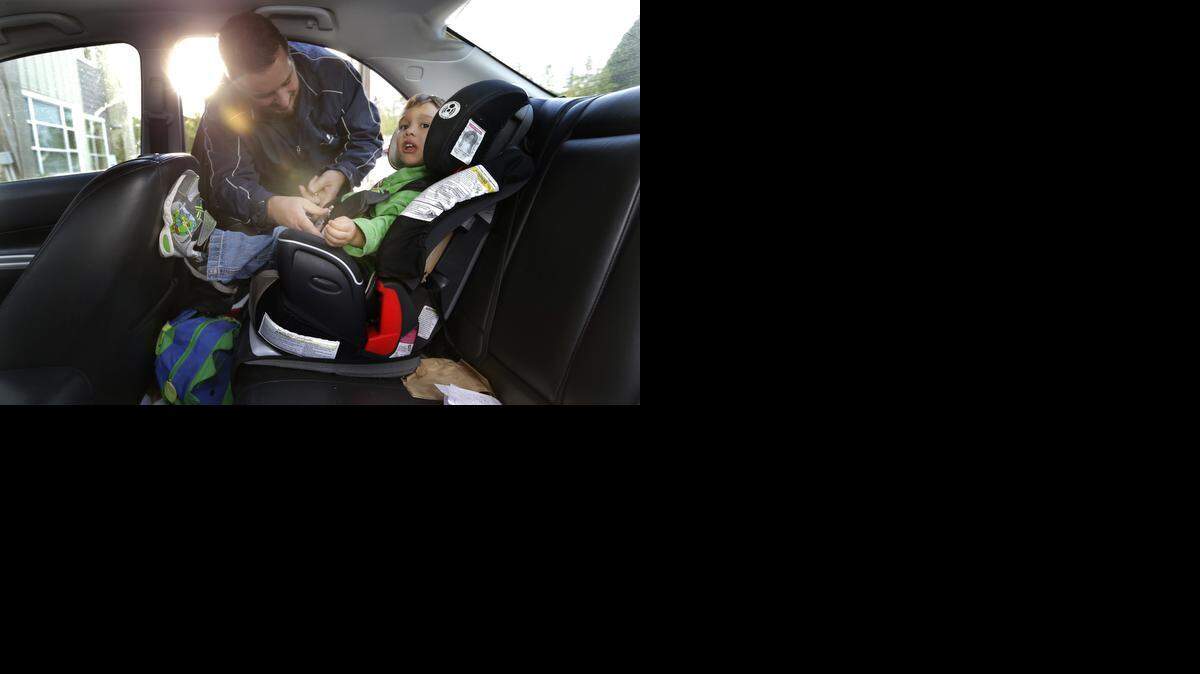 
Jason Prosser buckles in his son Zachary, 3, after picking him up from day care, in SeaTac, Wash. Prosser and his wife are one of many middle-class couples struggling with accelerating costs for critical services such as health care and child care.
