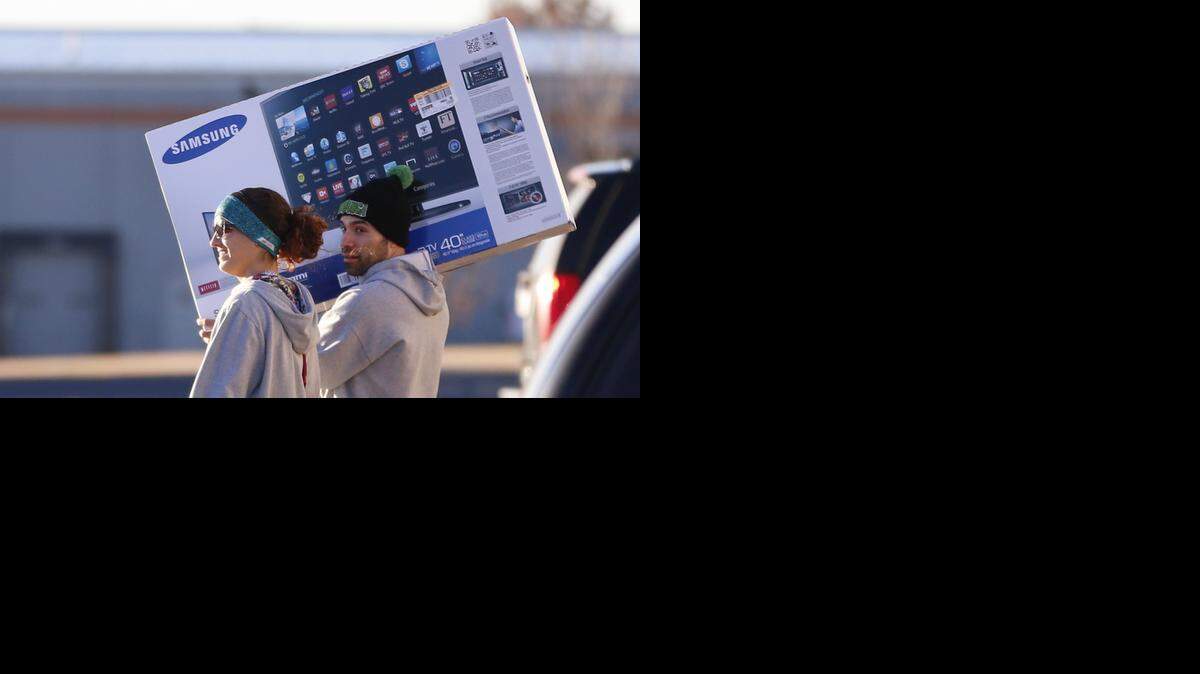 
A couple carries their new TV through a Wichita Target parking lot near Maple and Ridge on Friday morning after taking advantage of Target’s Black Friday sale.
