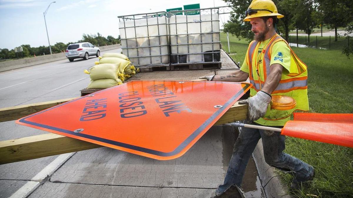 A construction worker carries a sign to position on Kellogg as work begins in August 2015 to repair six bridges in Wichita. Kansas Contractors Association Vice President Bob Totten says cuts to transportation funding are sending construction workers to other states to find jobs.