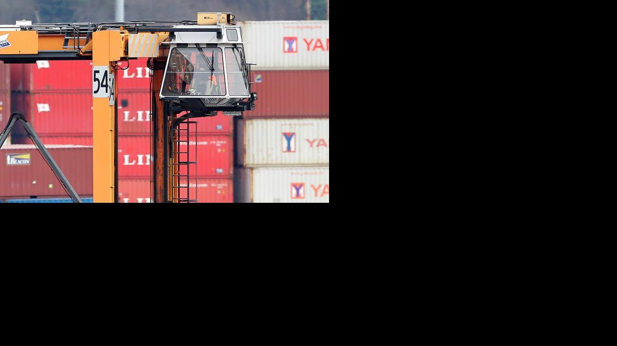 
A driver sits high in the cab of a cargo container mover at the Port of Tacoma, in Tacoma, Wash., on Saturday. Most dockworkers were back on the job this weekend, after negotiators reached a tentative deal.
