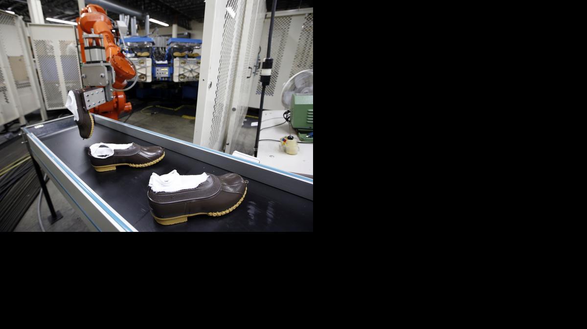 
Rubber bottoms of future L.L. Bean boots are dropped onto a conveyor belt by a robotic arm after the sole came out of a molding machine at a facility in Lewiston, Maine. The Maine-based retailer can’t make enough of its iconic boots to keep up with demand this holiday season.
