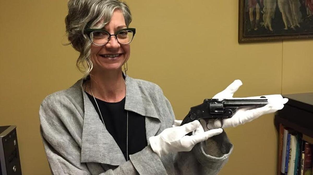Jami Frazier Tracy, curator of collections at the Wichita/Sedgwick County Historical Museum, displays a Smith and Wesson .38 revolver used by Wichita police Detective D.C. Stuckey, who fatally shot gangster Eddie Adams.