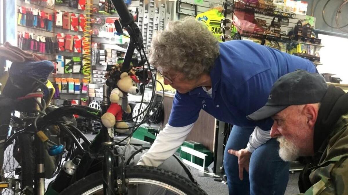 Ruth Holliday, owner of the Bicycle Pedaler shop, talked homeless man Keith Callison (right) into letting her staff repair the bike he rode here from California last summer.