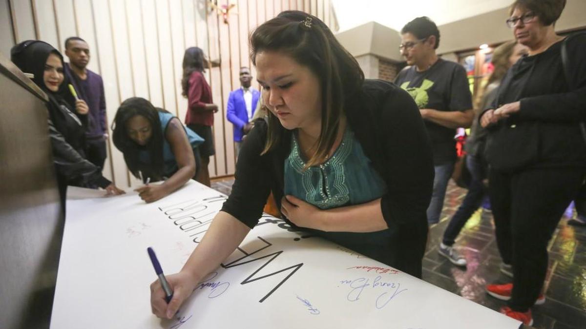 
Wichita State students, faculty and alumni sign a banner that reads “We support interfaith dialogue” after an event called “Prayers with the President” at Grace Chapel on Friday night. Grace Chapel, along with the university, have been under pressure lately after pews were removed from the chapel to make it more accessible to students of all faiths.
