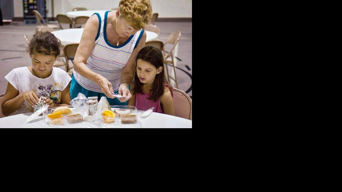 
Marita Flanigan helps her granddaughters Sophia Flanigan, left, and Trinity Flanigan, with their sandwiches during the first day of the Federal Summer Meals program at West Side Christian Church in 2010. The meals for the city-wide free summer breakfast and lunch program are prepared by USD 259.
