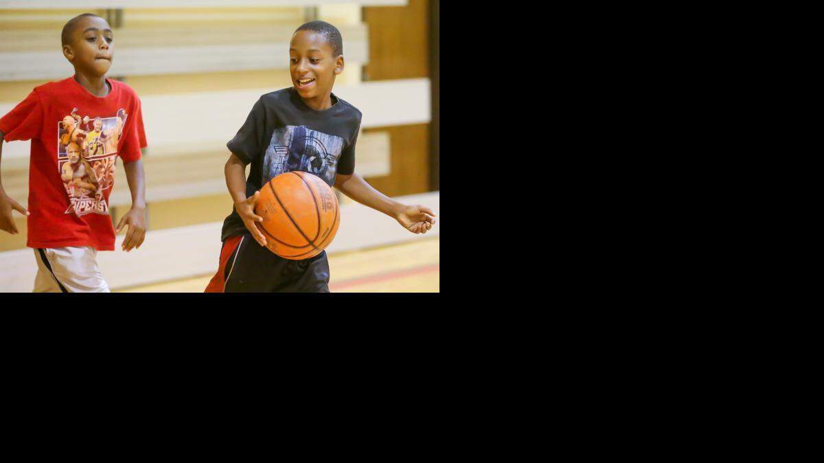 
Chase Harris, left, 9, and Isaiah Mims, 12, play some basketball at the Champion Church Gym as part of the Pickup Game basketball and mentorship program. (July 8, 2014)
