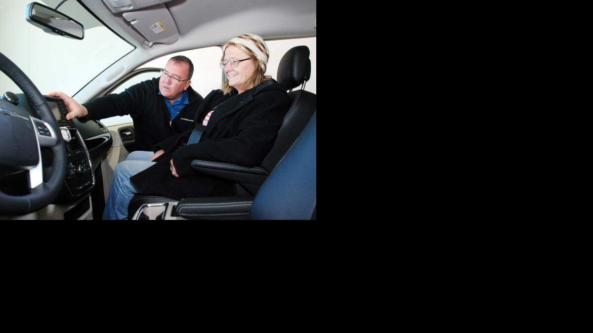 
Davis-Moore salesman Carl Sheel points out details of a Chrysler van to customer Linda Mitchell on Saturday morning.
