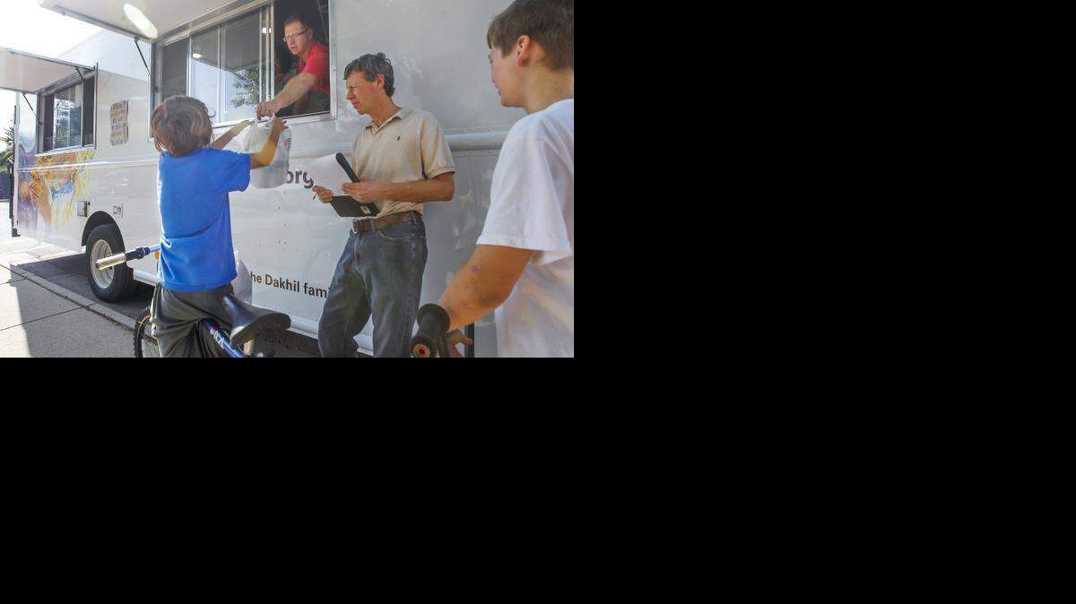 
A couple of teenagers on bikes pick up some meals from the Lord’s Diner truck that stopped at the Hilltop Center on Thursday. (Sept. 25, 2014)
