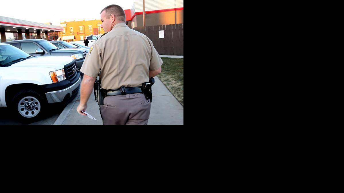 
Wichita police Officer Mike Brown looks for parked cars that are idling at a QuikTrip parking lot, leaving warning notes on those that were. 
