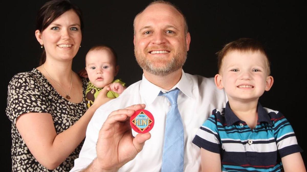 Matt Dwyer holds the medallion in the 2016 Eagle Medallion Hunt that he found in Edgemoor Park on Friday. With him are his wife, Ashley, and sons Charlie and Max.