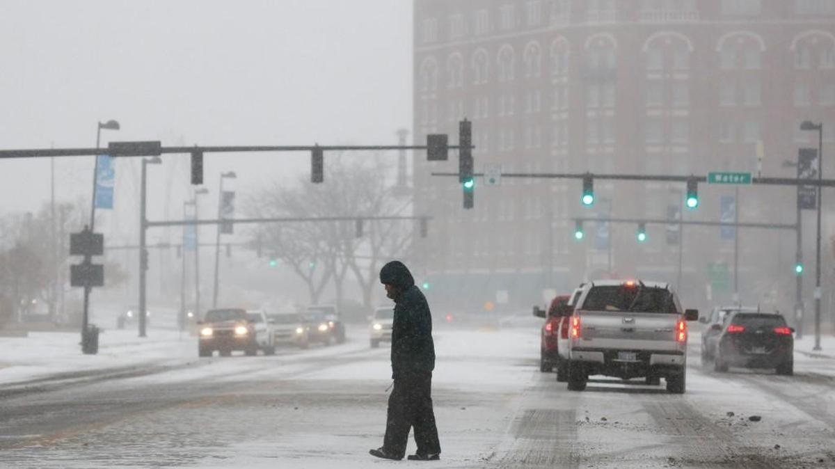 A pedestrian crosses Douglas as snow flurries get heavier in downtown Wichita on Saturday.