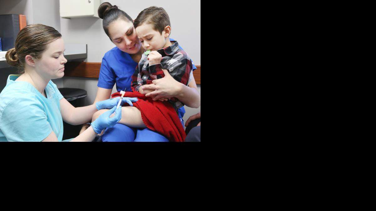 
RN Stacia Hobbs gives Rudy Garcia, 4, a booster shot Thursday at Redbud Pediatrics. Holding him is his mother, Megan Garcia, who also works at Redbud Pediatrics. (February 12, 2015)
