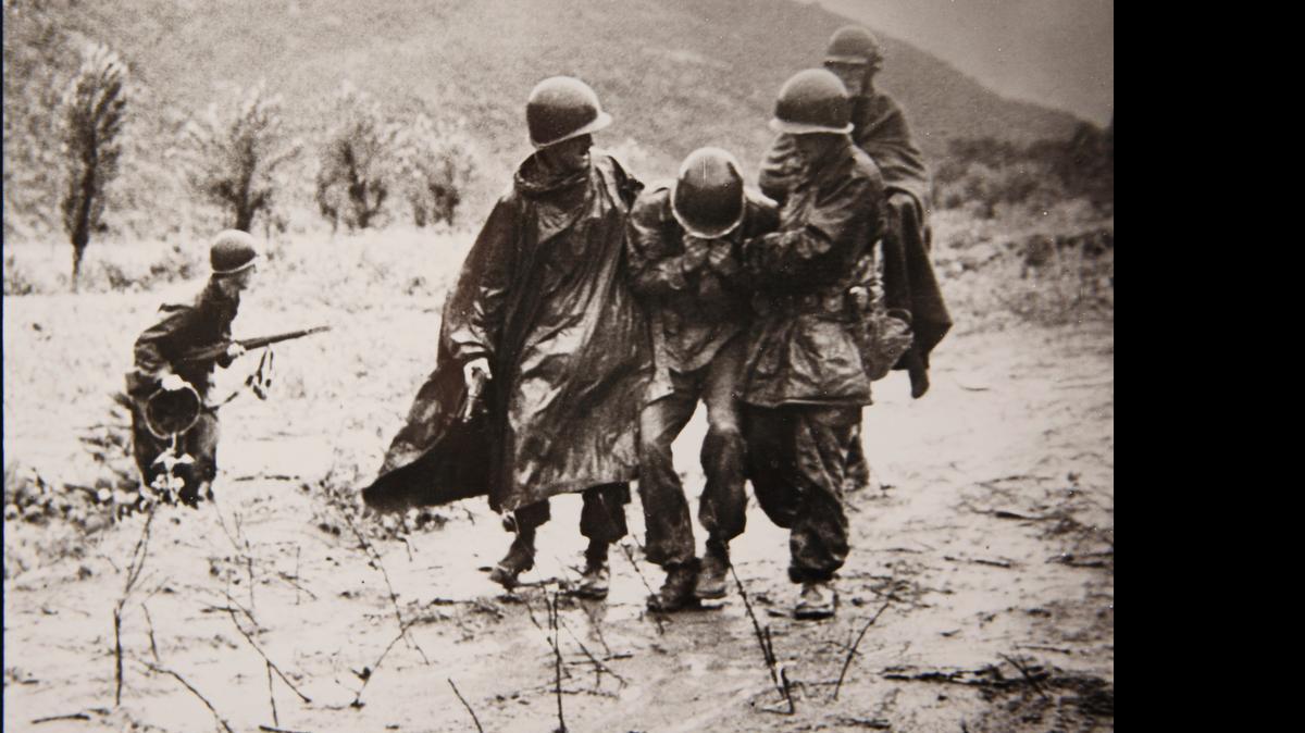 
One of two iconic photographs of Father Emil Kapaun, right, shows him and another soldier carrying an exhausted GI off a battlefield in Korea early in the war. The soldier on the GI’s other side was Capt. Jerome A. Dolan, a medical officer with the 8th Cavalry regiment. 
