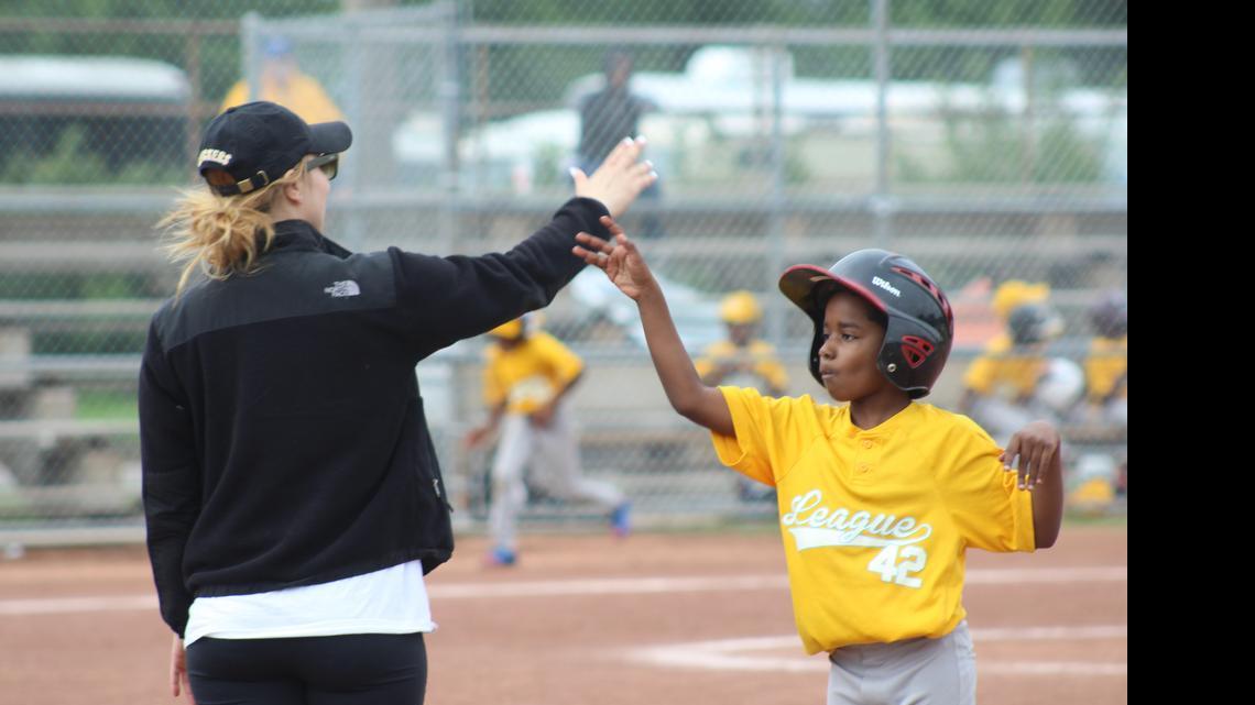 
A League 42 player high-fives one of his coaches after successfully making it to first base during a game Saturday afternoon. 
