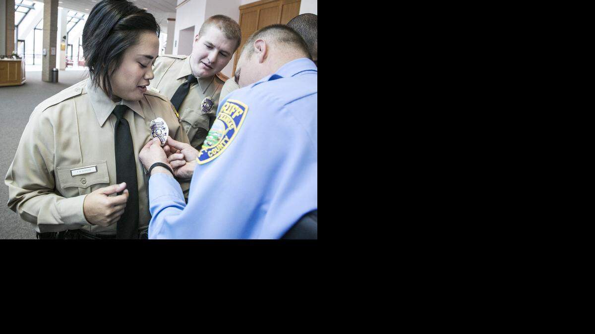 
Sheriff’s deputy graduate Michael Jausel, right, helps Wichita police graduate Tracy Gupilan with her badge. Thirty-two new law enforcement officers graduated from the Wichita-Sedgwick County Law Enforcement Training Academy on Friday. 
