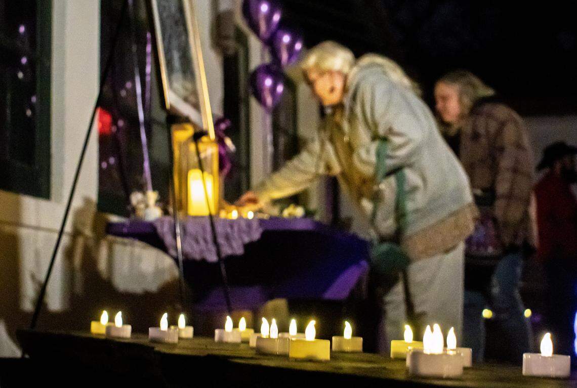A woman picks up a vigil keepsake made by Ian Shelton's friend Jessica Simons. More than 50 attended Saturday's vigil honoring Ian Shelton, who disappeared on Dec. 3.