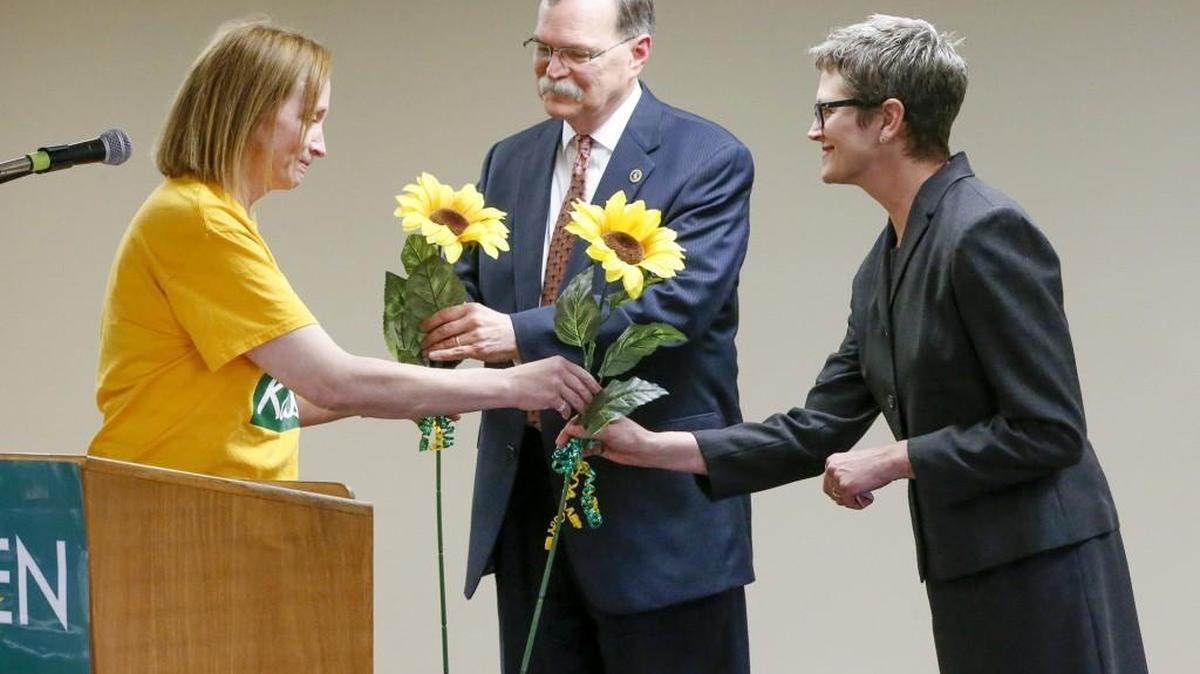 Kansas Supreme Court Chief Justice Lawton R. Nuss, center, and Justice Carol A. Beier, right, receive sunflowers from Women for Kansas co-chair Martha Pint in appreciation for their discussion on the state of Kansas courts Saturday at the SEIU Hall.