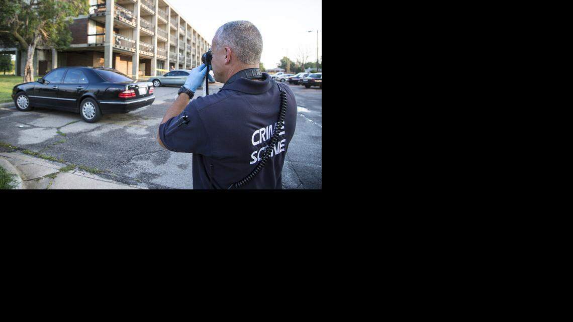 
Wichita police crime scene Investigator Kevin Brasser photographs the scene of a triple shooting at the Calvary Towers apartments in the 2600 block of North Grove on Thursday morning. (Aug. 7, 2014)

