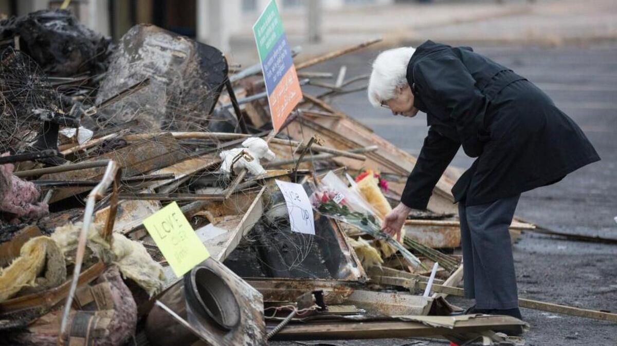 JoLin Gardner places a bouquet of flowers on a pile of debris outside of Petra Restaurant on Friday. A prayer vigil was held outside of the restaurant on Friday, a couple of days after it was destroyed by fire and the words “Go Back” were spray-painted in the back of the building. Officials say the fire was intentionally set.