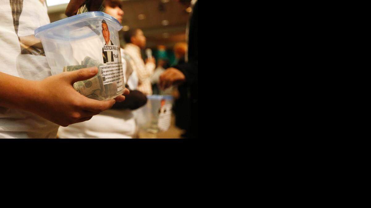 
Family members hold containers for donations during a vigil for John Paul Quintero, who was killed in a officer-involved shooting on Jan. 3. (January 7, 2015)
