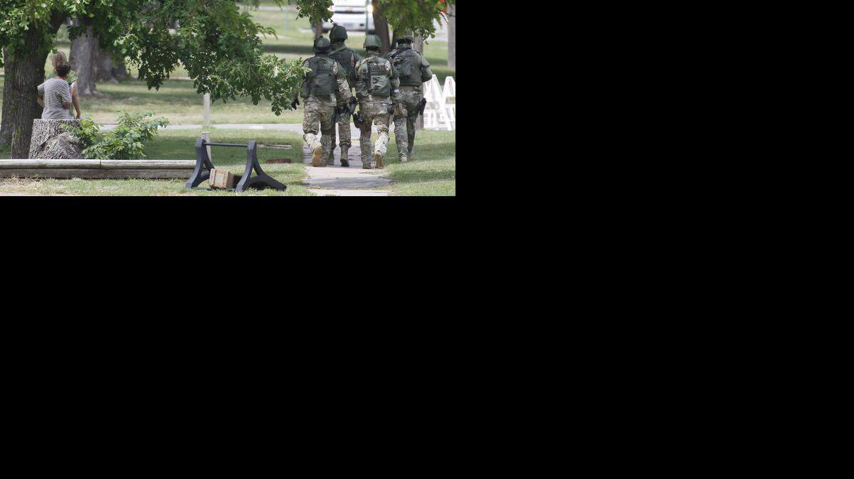 
Onlookers watch as SWAT team members take positions around a house in Goddard during a search for a robbery suspect. (May 21, 2014) 
