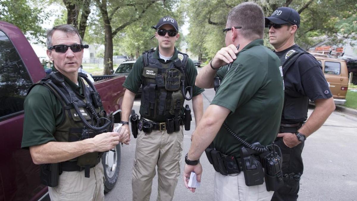 Four Wichita police officers conduct an investigation in front of a home on South Mosley. At far left is Wichita police Officer Brian Arterburn.