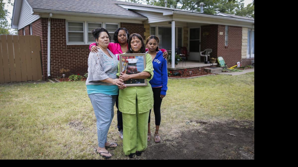
Standing in her front yard, Beverly Allen holds a picture of her son, Icarus Randolph, while surround by her daughters Ida Allen, left, Elisa Allen, middle and Briana Alford. All four were witnesses when Icarus Randolph was shot and killed by a Wichita police officer last July. (Sept. 24, 2014) 
