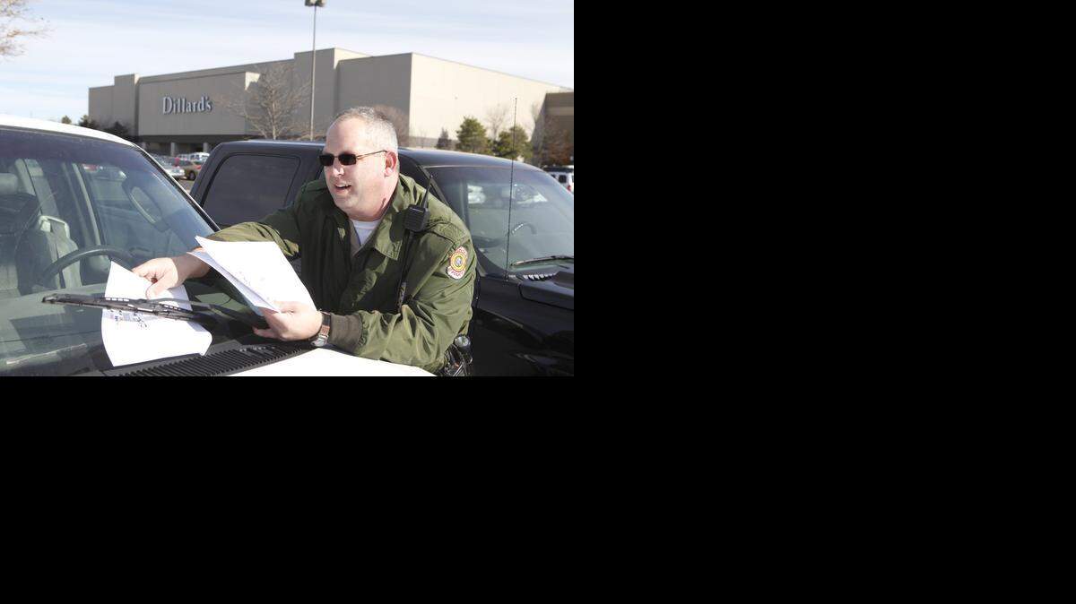 
Community Policing Officer Mike Lloyd placed flyers on the windshields of cars parked at Towne East Square. The flyers reminded people to cover their valuables in the car or place them in the trunk to protect them from thieves. (Nov. 28, 2011)
