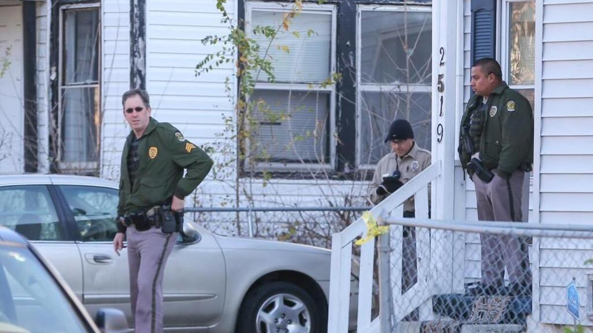 Police stand outside of a home at East Mossman where two people were fatally shot Tuesday.
