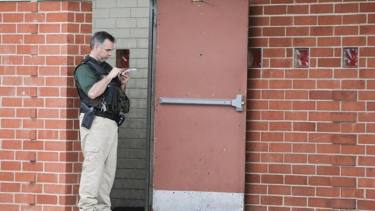 A Wichita police officer stands outside the entrance of a party venue beneath Parrot-fa-Nalia Unique Boutique, where 17-year-old Leon McClennon died in a shooting on May 9, 2015.