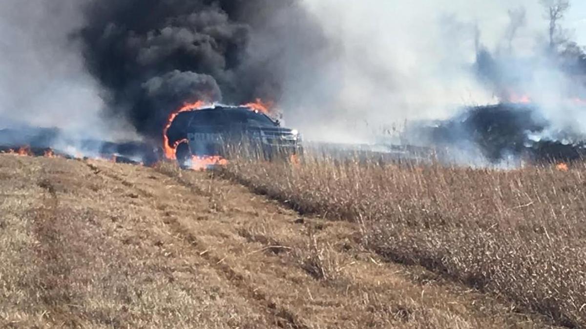 A Hesston police patrol car burns in the weeds next to I-135 near Moundridge on Thursday afternoon. Heat from the car’s undercarriage ignited the weeds.