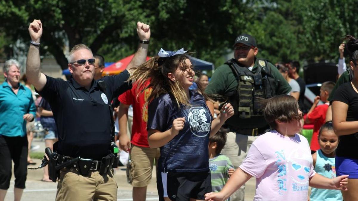 Sedgwick County sheriff’s Deputy Tim Hallacy, left, dances at the Love Your Community cookout last year at the Evergreen center. (2016)