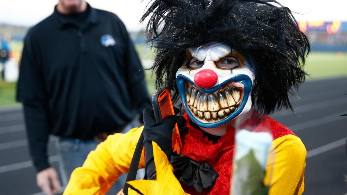 A fan at a high school football game wears a scary clown mask in 2015.
