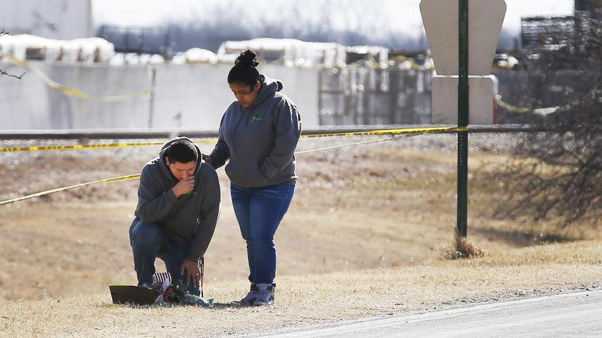 A couple stops to leave flowers on the roadside near Excel Industries on Friday morning. Three people were killed and more than a dozen injured Thursday after Cedric Ford returned to work and began shooting. Ford was killed by a police officer.