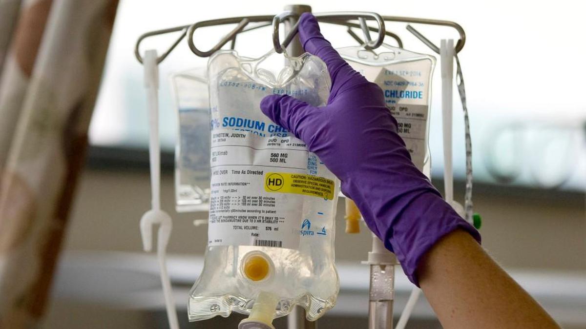 A nurse places a patient’s chemotherapy medication on an intravenous stand.