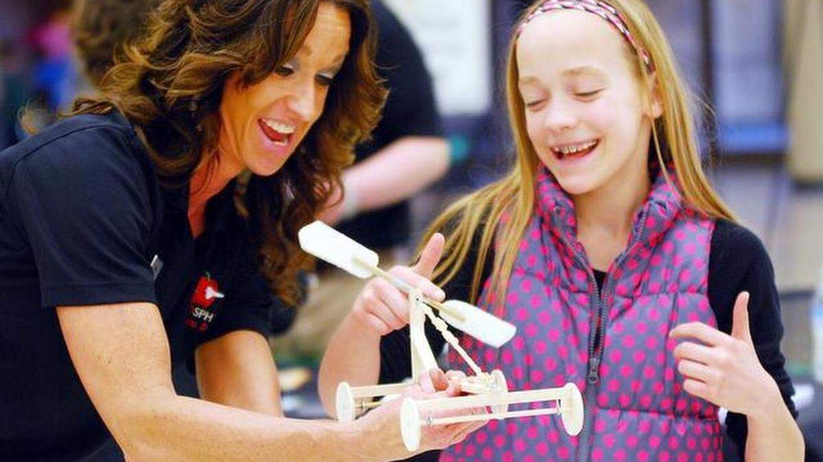 Cheri Hastert, left, helps Finley Buckingham with a wind-up car at the Wichita Society of Women Engineers Engineering Expo at Century II. Hastert is from the Kansas Cosmosphere. (Feb. 21, 2015)