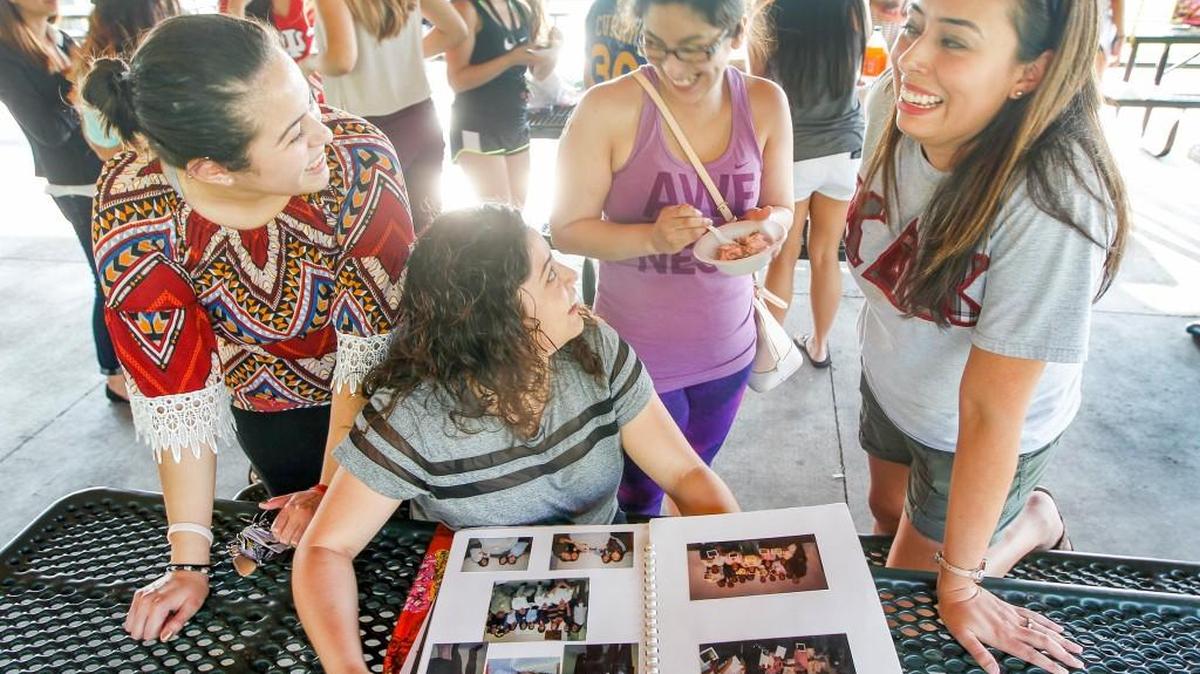 
Lili Montiel, left, and Idalia Loya, second from left, of the Latina Interest Association look at photo albums and share stories with alumni Olga Salazar, second from right, and Haydee Serna, who started a Latina Kappa Delta Chi sorority in 2000, while attending a thank-you dinner for the Multicultural Greek Council at Chisholm Creek Park. (Aug. 13, 2015)
