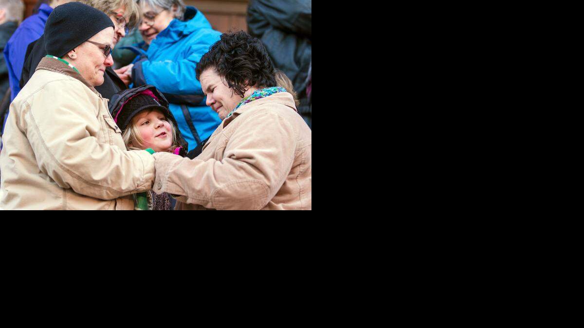 
Krista Casmaer, left, and Mindy Kufahl trade wedding bands Monday with Kufahl’s daughter Phoebe Edgerton-Kufahl, 7, as witness during a mass same-sex marriage ceremony on the steps of the Historic Sedgwick County Courthouse. (Nov.17, 2014)
