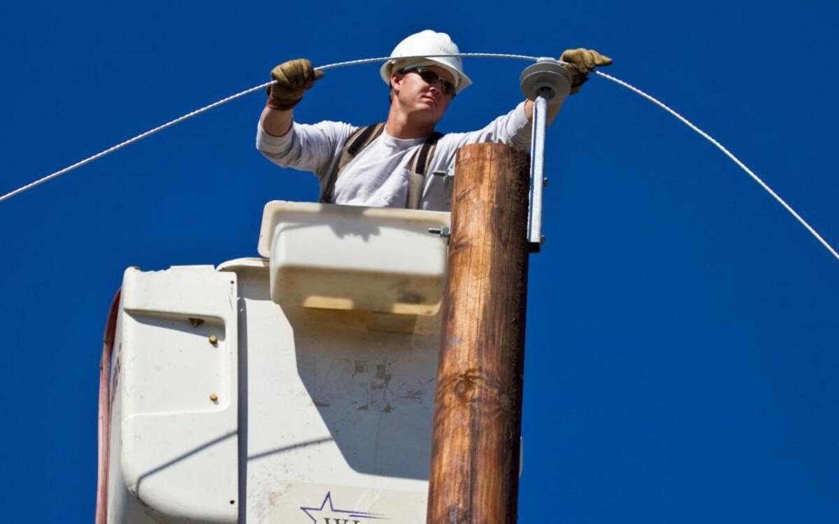 A Westar Energy worker handles a new power line in this file photo. The company says it will get half the power it sells from zero-emission sources by next year.