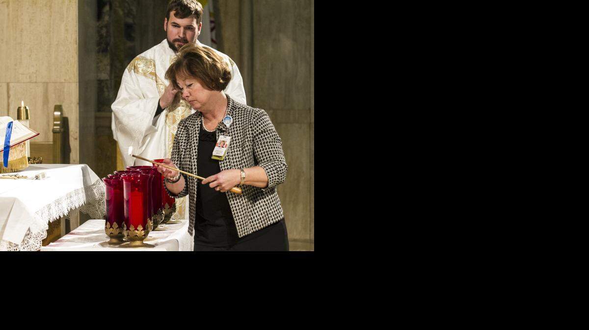 
Laurie Labarca lights a candle at Via Christi St. Francis during a special Mass and prayer service on Feb. 9 for human trafficking victims in the Chapel of the Sorrowful Mother. Behind her is the Rev. Jeremy Huser. The Mass was part of the celebration of the feast day, or remembrance, of St. Josephine Bahkita, a Sudanese-born former slave who is the patron saint of human trafficking victims. 
