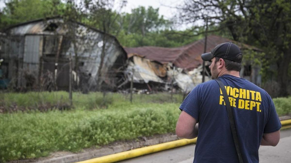 Wichita firefighter Brock Johnson monitors the scene of an overnight fire at the former Joyland amusement park Tuesday morning. The fire was reported around midnight and firefighters found a storage building in the old Frontier Town area engulfed in flames. (April 26, 2016)