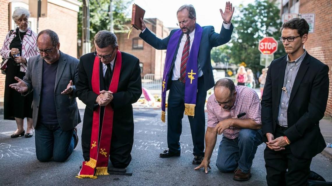 Ministers and representatives of several churches pray together at the site where on Saturday a car plowed into a group of counter-protesters after a "Unite the Right" rally by white nationalist groups, in Charlottesville, Va., Aug. 13, 2017. A woman was killed and at least 19 were injured, and the car's alleged driver has been charged with second-degree murder. (Edu Bayer/The New York Times)