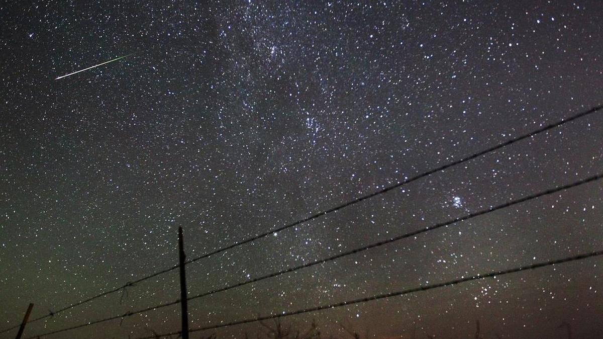 In this file photo from Aug. 13, 2013, a meteor streaks past the faint band of the Milky Way galaxy above the Wyoming countryside during a Perseids meteor shower.