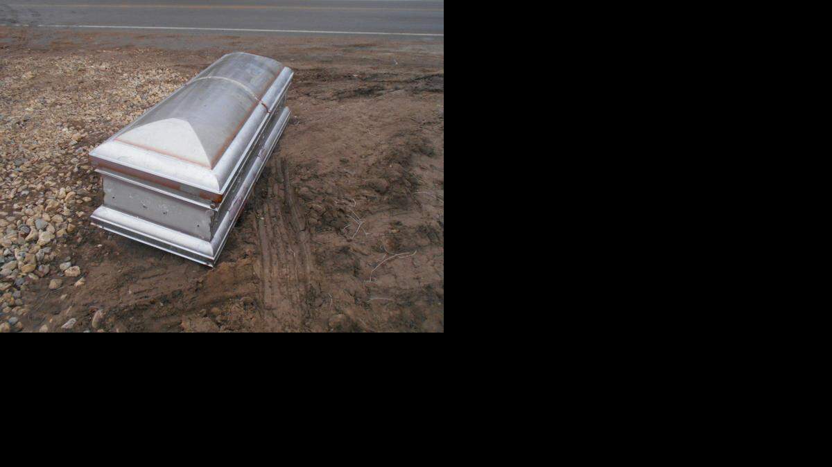 
In the photo, the handles on the side of the metal casket have been removed, and the lid has been pried open.
