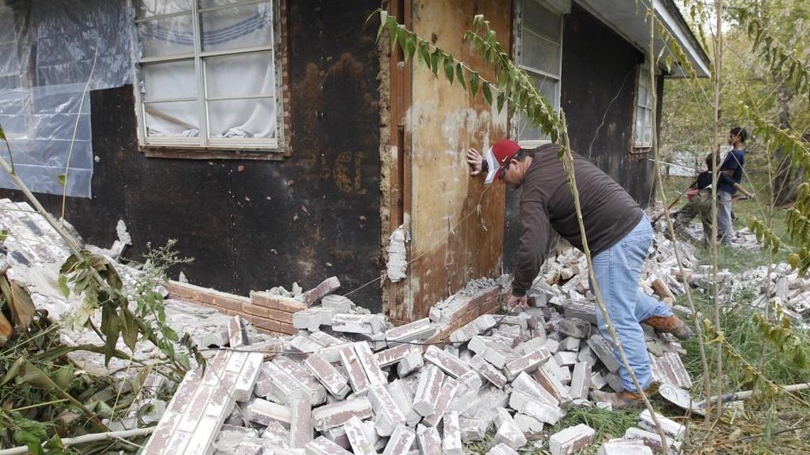 In this Nov. 6, 2011, photo, Chad Devereaux examines bricks that fell from three sides of his in-laws’ home in Sparks, Okla., after two earthquakes hit the area in less than 24 hours.