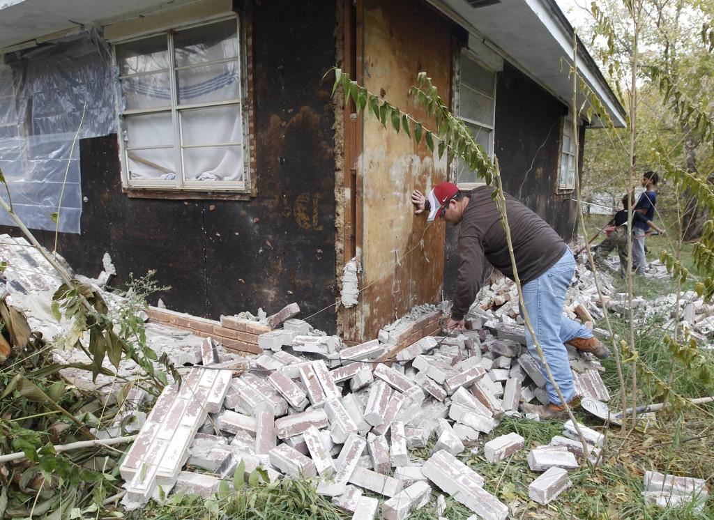 In this Nov. 6, 2011, photo, Chad Devereaux examines bricks that fell from three sides of his in-laws’ home in Sparks, Okla., after two earthquakes hit the area in less than 24 hours.