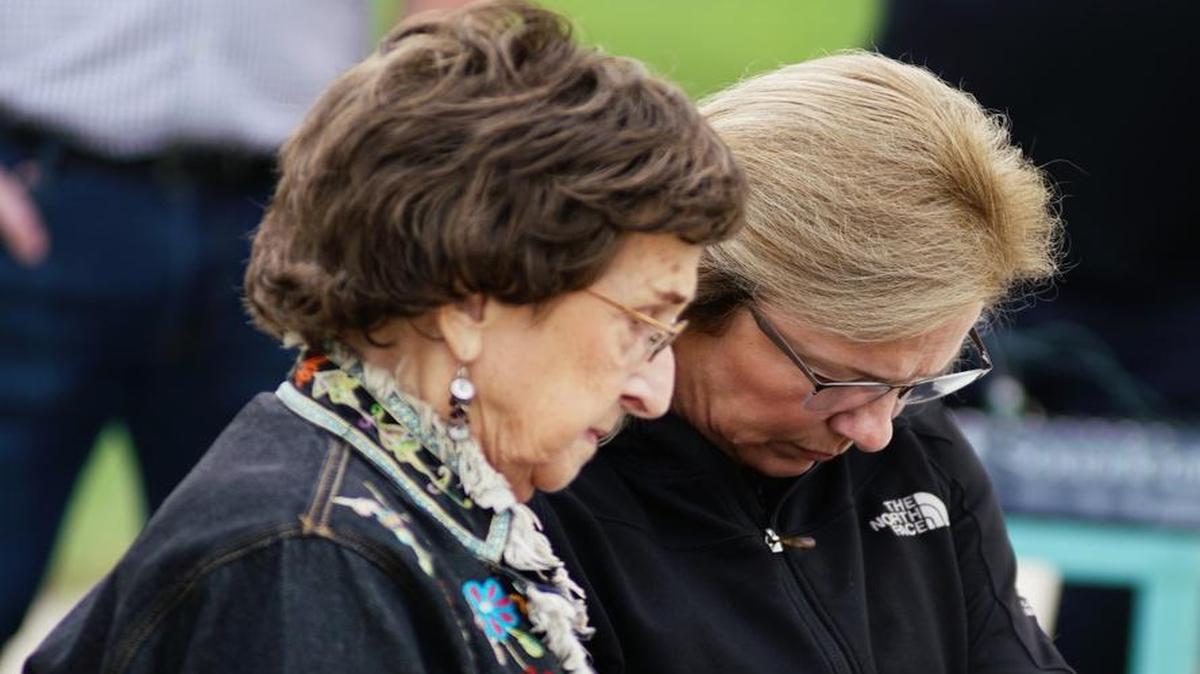 Family members and friends hold hands in prayer during the annual memorial service for the 1970 plane crash that killed 31 people. (October 2, 2016)